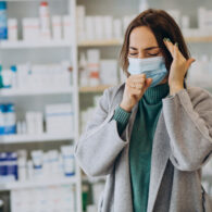 Женщина с головной болью и в маске в аптеке