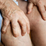 пожилая женщина держит руки на коленях